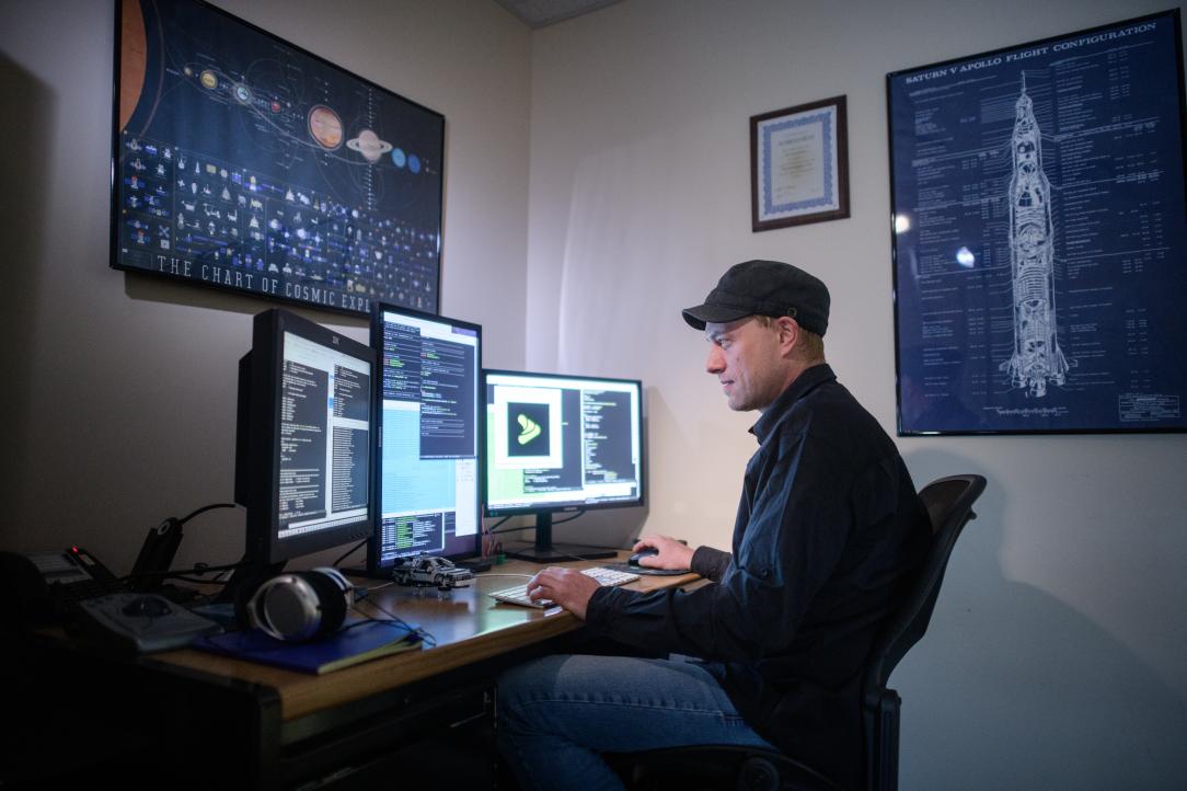software developer coding on three screens