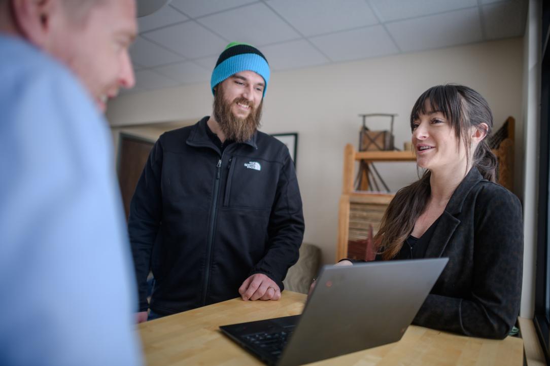 three colleagues having a discussion over a laptop