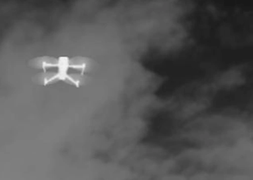 Thermal/infrared view of a drone flying in cloudy conditions.
