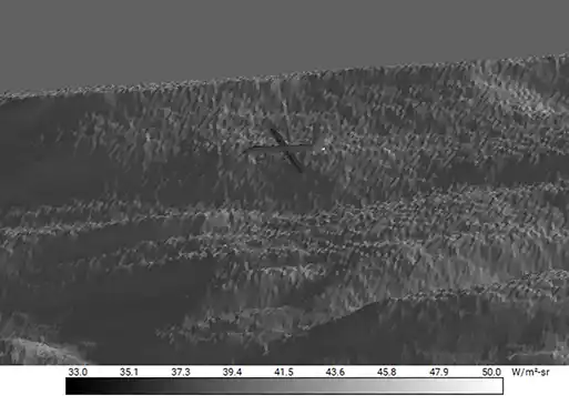 Infrared aerial view of terrain with aircraft silhouette and radiance scale.
