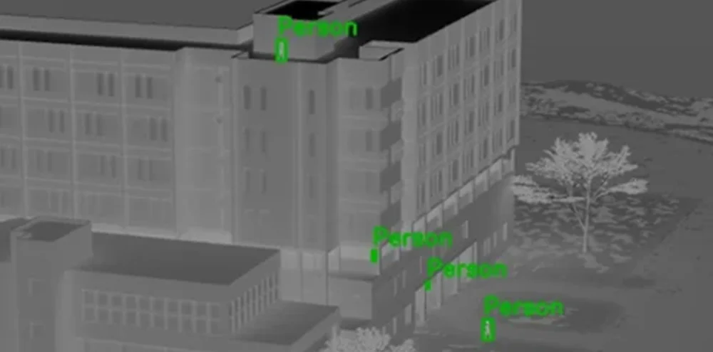 Thermal simulation of a building scene highlighting multiple people detected around the structure.